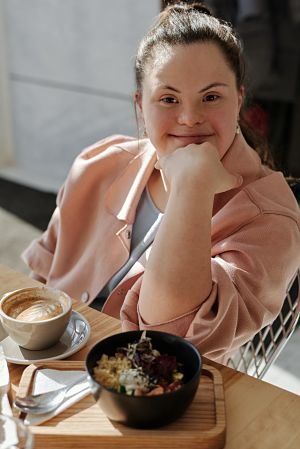 Woman with Down syndrome having coffee and a bowl of food.