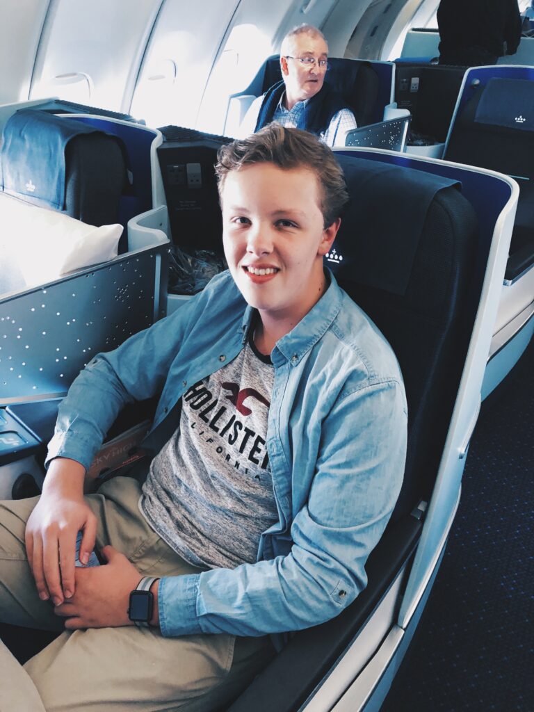 Young man seated on airplane with a smile on his face.