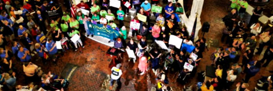 Photo from above of a large crowd of people at a public event. Many people are holding signs.