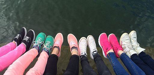 Photo of many different colored shoes and peoples legs as they are about to walk together in community.