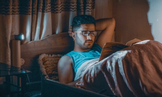 Photo of young, tan man reading a book in late evening before bed.