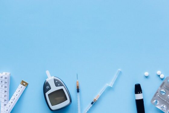 Image of insulin injections, insulin pen, diabetes test kit, supplies scattered over blue background