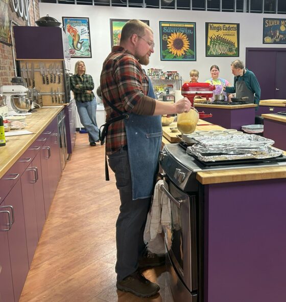 Photo of instructor pouring custard into the baking dishes as attendees watched and learned about the process. 