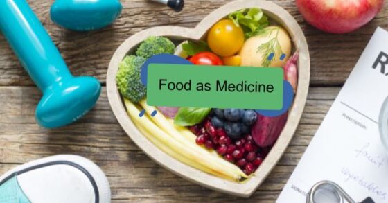 Image of a heart shaped wooden bowl full of vibrant clorful fruits and vegetables like broccoli, tomatoes, pomegranates, blueberries, potatoes, and beans. Surrounding this bowl you can partially see a red apple, blue hand weights, blue tennis shoes and a doctor's prescription pad. A green and blue text box reads "Food as Medicine" 