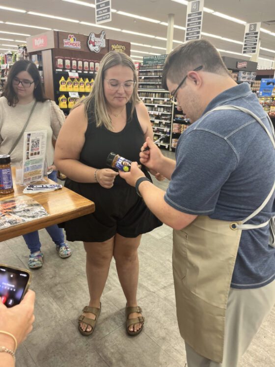 Photo of Max signing a bottle of Max Mix for a customer in the grocery store. 