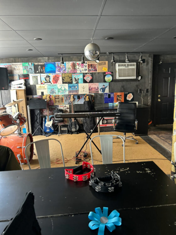 Photo of music room at Purple Cat containing drum set, keyboard, tambourines, and various decor including silver disco ball. 