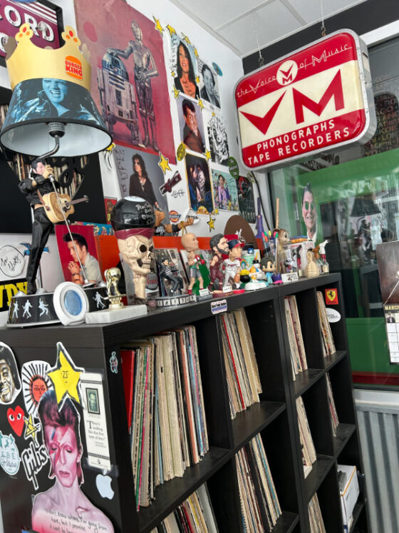 Photo of wall at Purple Cat holding many posters and shelves full of vinyl records and pop culture memorabilia. 